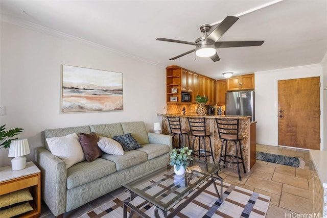 living room featuring ceiling fan, ornamental molding, and stone tile flooring