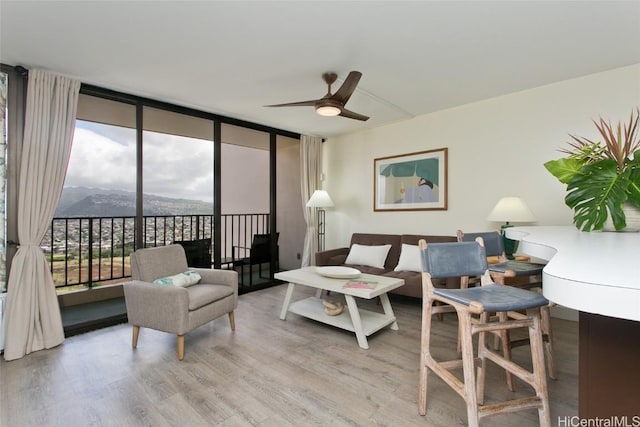 living room featuring a mountain view, wood finished floors, a ceiling fan, and expansive windows