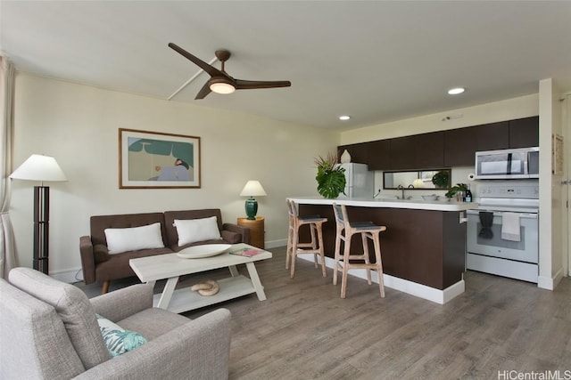 living room featuring recessed lighting, wood finished floors, baseboards, and ceiling fan