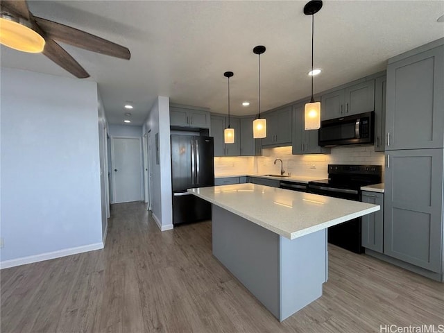 kitchen with a center island, light countertops, backsplash, a sink, and black appliances