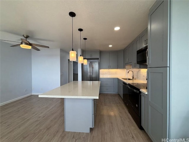 kitchen featuring a center island, light wood-type flooring, gray cabinets, decorative backsplash, and black appliances