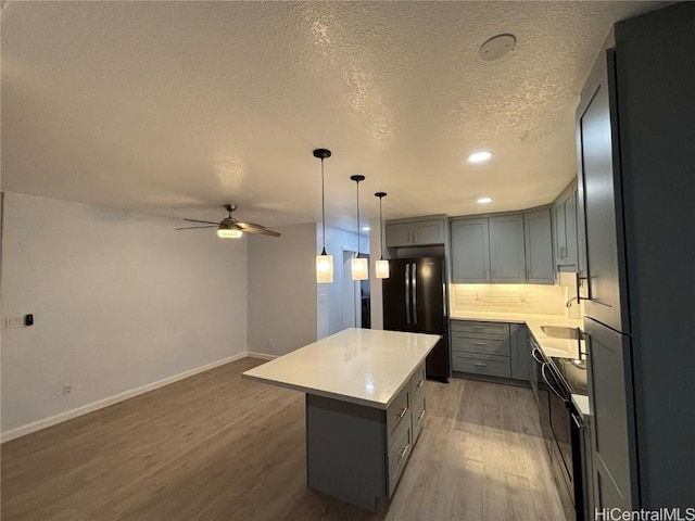 kitchen with refrigerator, light wood finished floors, gray cabinets, freestanding refrigerator, and a kitchen island