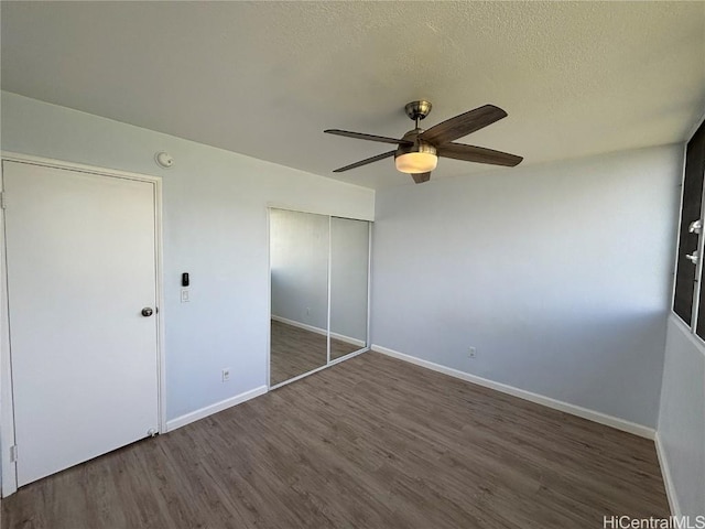 unfurnished bedroom featuring a closet, a textured ceiling, baseboards, and wood finished floors