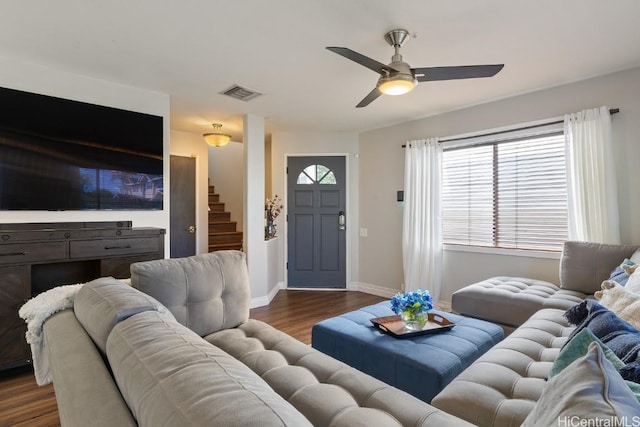 living room featuring visible vents, dark wood-type flooring, stairway, baseboards, and ceiling fan