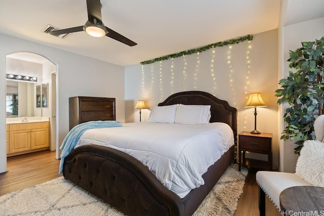 bedroom with connected bathroom, visible vents, light wood-style flooring, and ceiling fan