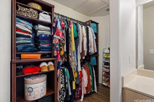 walk in closet with visible vents, attic access, and wood finished floors