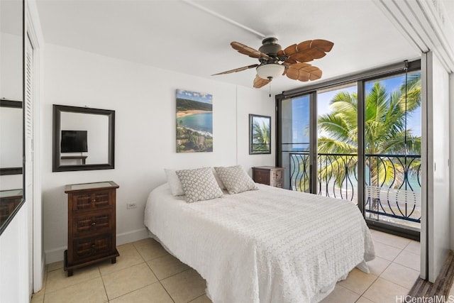 bedroom featuring access to exterior, light tile patterned floors, ceiling fan, a wall of windows, and baseboards