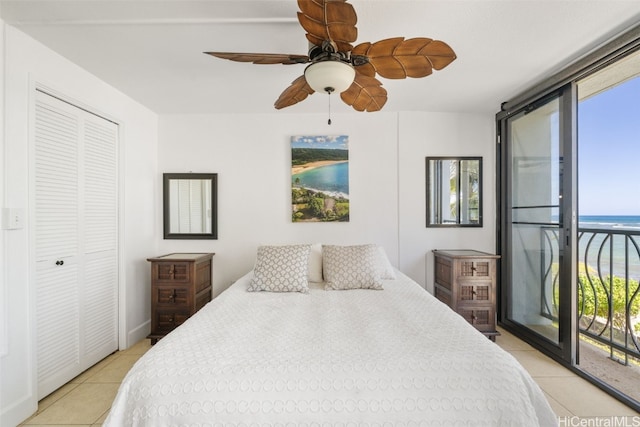 bedroom featuring light tile patterned floors, a water view, a ceiling fan, access to exterior, and a closet