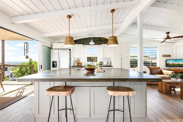 kitchen featuring stainless steel fridge, dark countertops, a healthy amount of sunlight, and white cabinetry