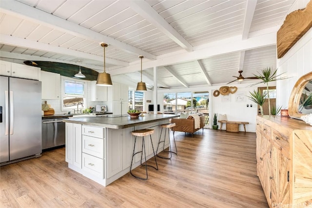 kitchen featuring open floor plan, a center island, stainless steel appliances, a breakfast bar area, and white cabinets