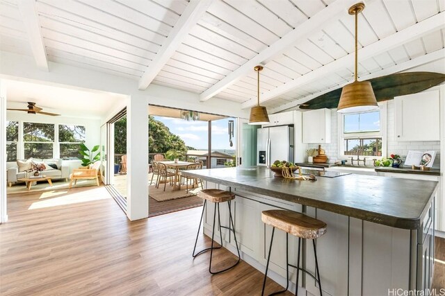 kitchen featuring light wood-style floors, vaulted ceiling with beams, stainless steel refrigerator with ice dispenser, and a healthy amount of sunlight