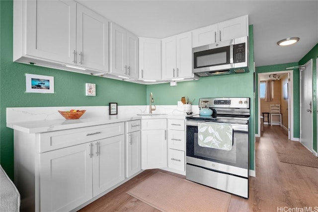 2211 Ala Wai Blvd Unit 2414, Honolulu, HI 96815 - kitchen with a sink, light wood-style flooring, appliances with stainless steel finishes, and white cabinets