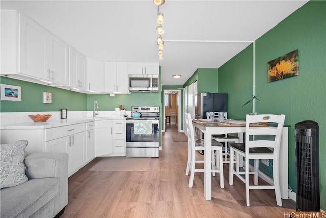 2211 Ala Wai Blvd Unit 2414, Honolulu, HI 96815 - kitchen featuring light wood finished floors, a sink, stainless steel appliances, white cabinets, and light countertops