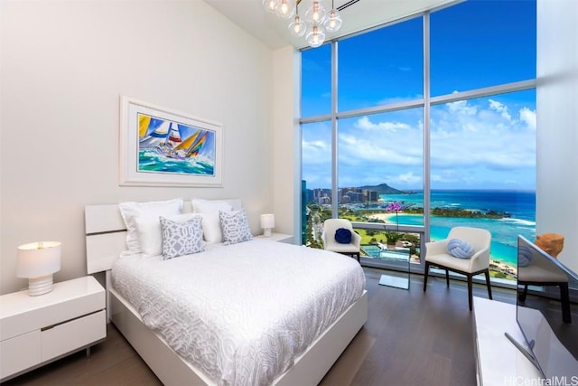 bedroom with an inviting chandelier, expansive windows, and dark wood finished floors