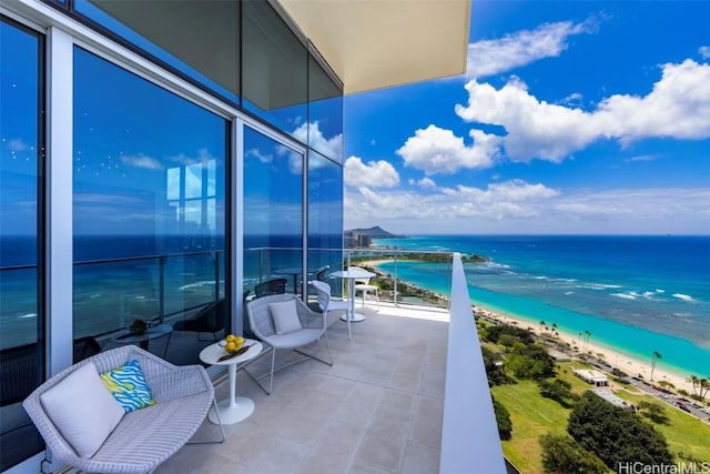 balcony with a water view and a view of the beach