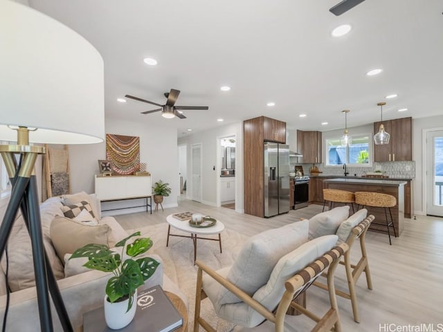 living area featuring light wood finished floors, recessed lighting, baseboards, and a ceiling fan