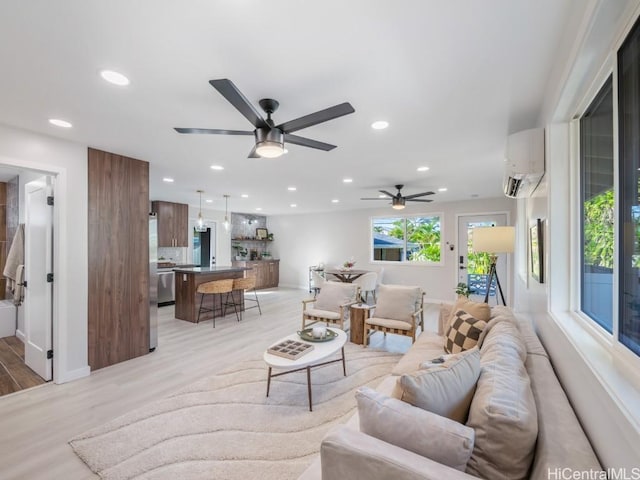 living room featuring recessed lighting, an AC wall unit, and light wood-style floors