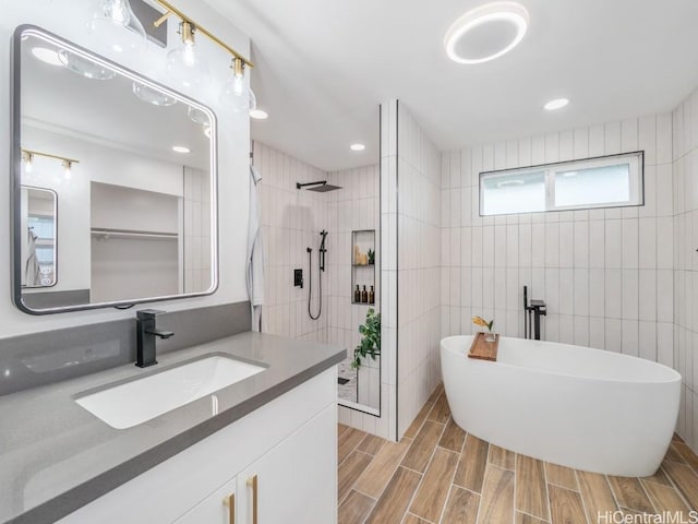 bathroom featuring wood finish floors, vanity, tile walls, and walk in shower