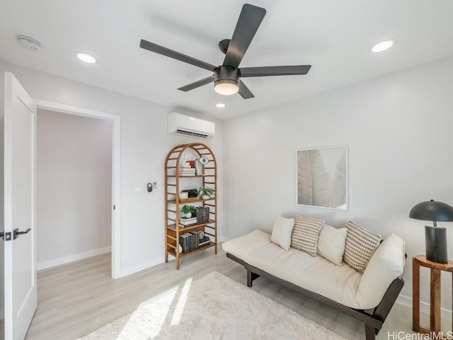 sitting room with baseboards, recessed lighting, an AC wall unit, and light wood-style floors