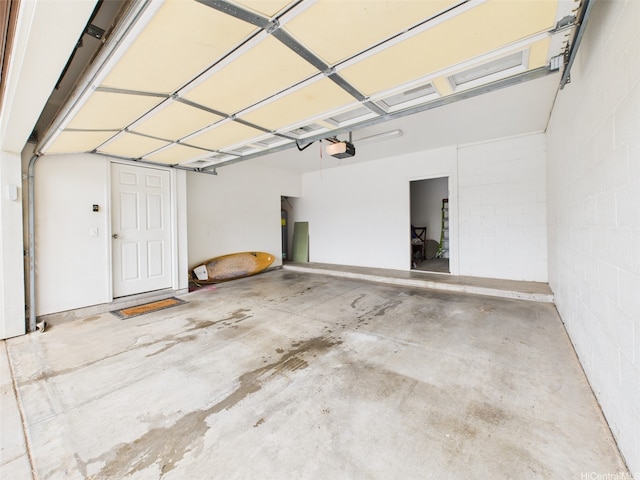 garage with a garage door opener and concrete block wall