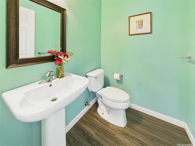 bathroom with toilet, baseboards, and wood finished floors
