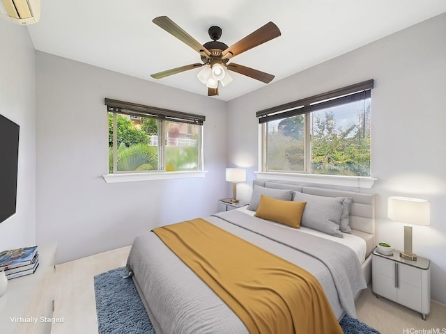 bedroom featuring a wall mounted air conditioner, a ceiling fan, and wood finished floors