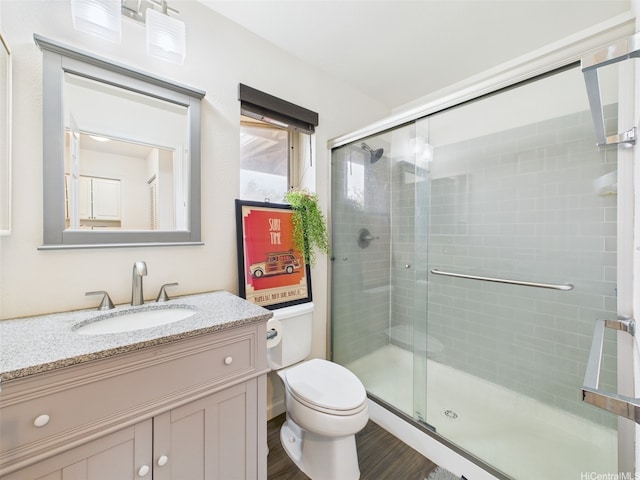 bathroom with toilet, a shower stall, vanity, and wood finished floors