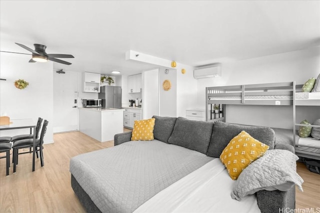 bedroom featuring an AC wall unit, freestanding refrigerator, and light wood-style floors