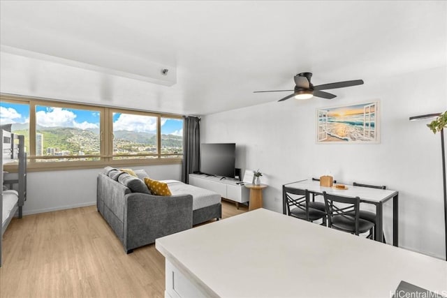 living area featuring light wood-style flooring, baseboards, and a ceiling fan