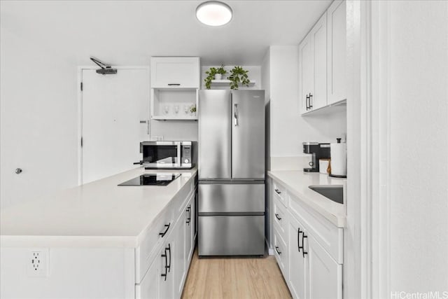 kitchen featuring light wood-style flooring, a peninsula, white cabinets, appliances with stainless steel finishes, and open shelves