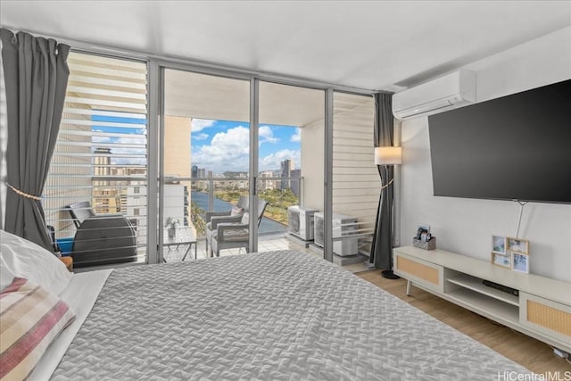 bedroom with a wall unit AC, access to outside, expansive windows, and wood finished floors