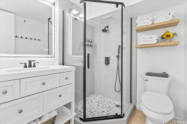 full bathroom featuring vanity, wood finished floors, a shower stall, and toilet