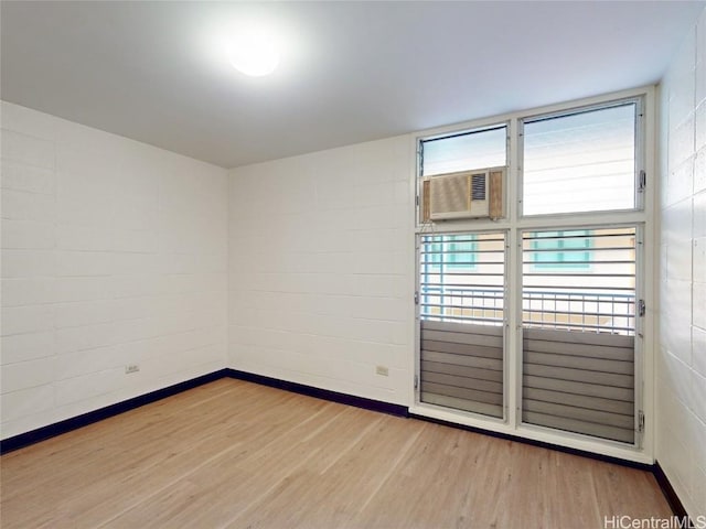 unfurnished room with cooling unit, baseboards, and wood finished floors