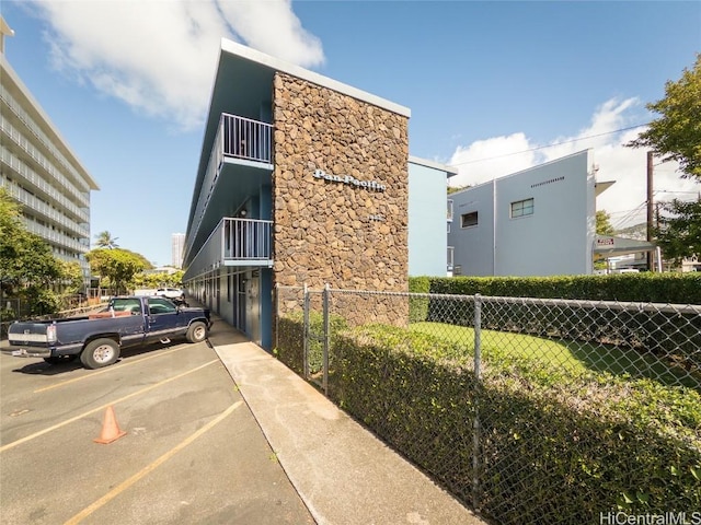 view of building exterior with uncovered parking and fence