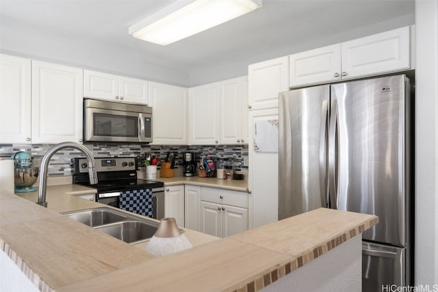 kitchen with tasteful backsplash, white cabinets, stainless steel appliances, light countertops, and a sink