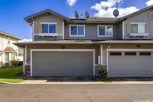 townhome / multi-family property with a garage, solar panels, and roof with shingles