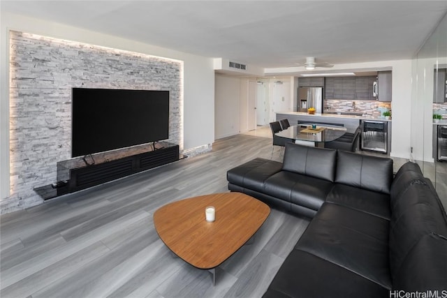 living room with light wood-type flooring, visible vents, and beverage cooler