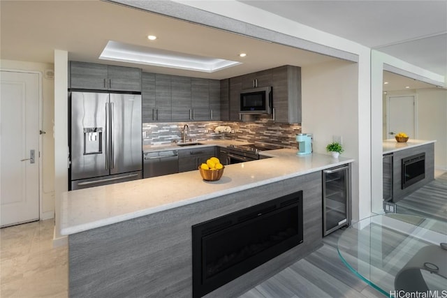 kitchen with a peninsula, stainless steel appliances, wine cooler, modern cabinets, and tasteful backsplash