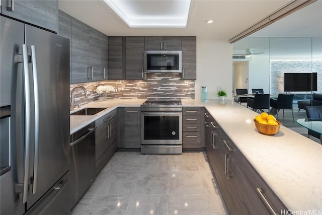 kitchen featuring backsplash, appliances with stainless steel finishes, light countertops, and a sink