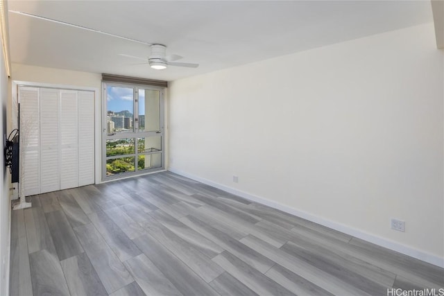 unfurnished room with ceiling fan, baseboards, and wood finished floors