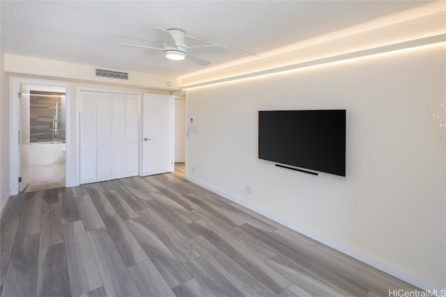 unfurnished bedroom with wood finished floors, baseboards, visible vents, ceiling fan, and a closet