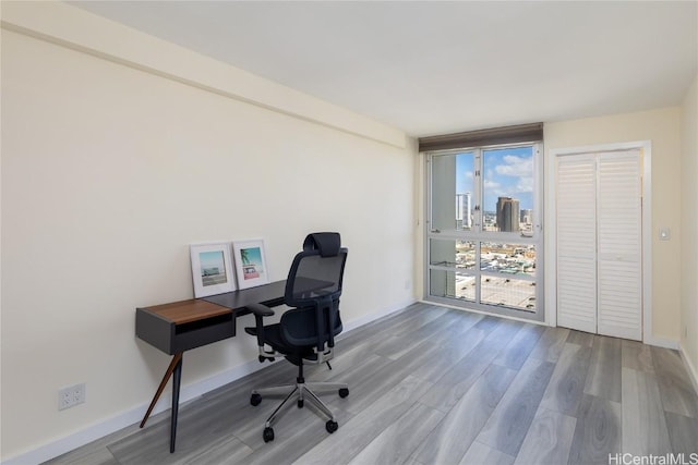 office area featuring a view of city, wood finished floors, and baseboards