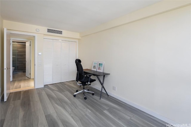 office space featuring wood finished floors, visible vents, and baseboards