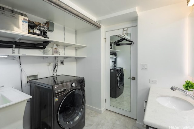 washroom with a sink, baseboards, laundry area, and washer and dryer