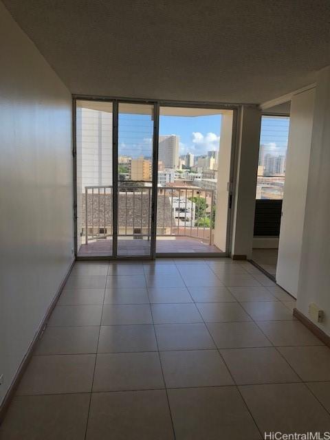 unfurnished room with a view of city, a wall of windows, tile patterned flooring, and baseboards