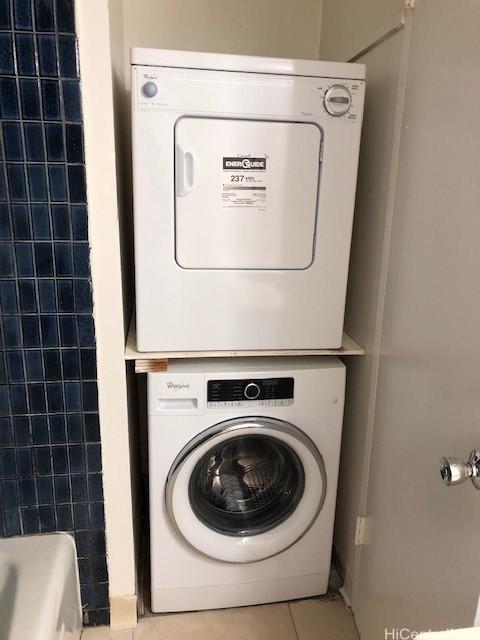 clothes washing area with laundry area, light tile patterned floors, and stacked washer / dryer