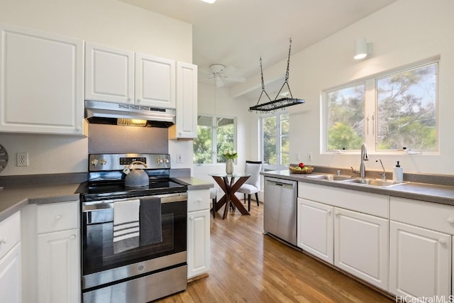 kitchen featuring appliances with stainless steel finishes, white cabinets, a sink, and under cabinet range hood