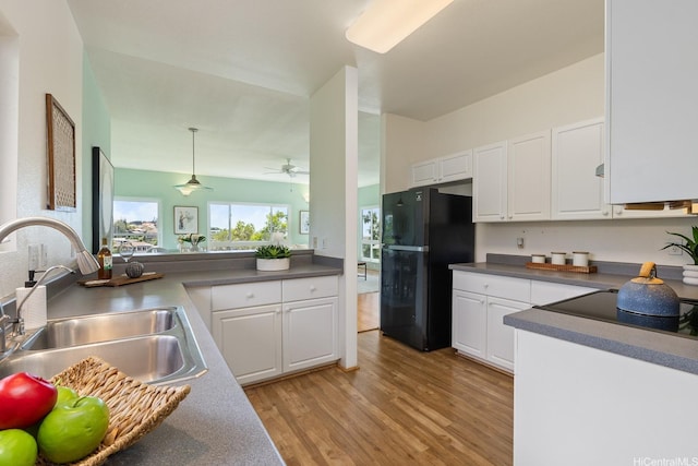 kitchen with a ceiling fan, light wood-style floors, white cabinets, a sink, and black appliances