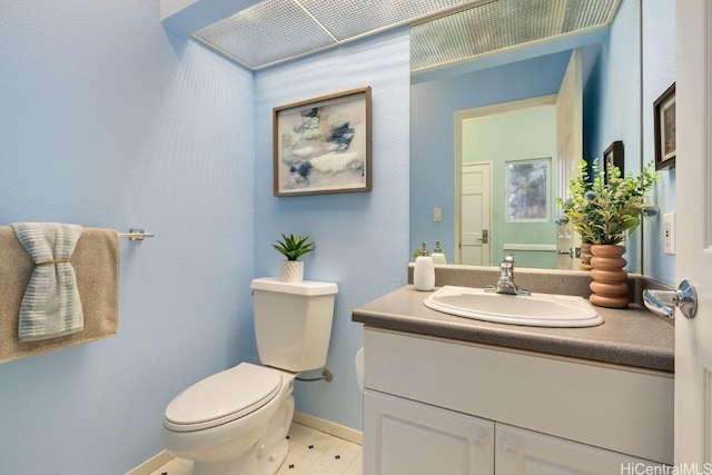 half bath featuring vanity, toilet, and baseboards