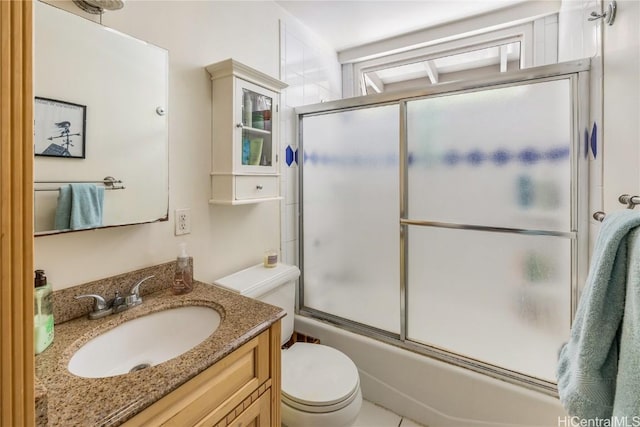 bathroom with toilet, vanity, and bath / shower combo with glass door